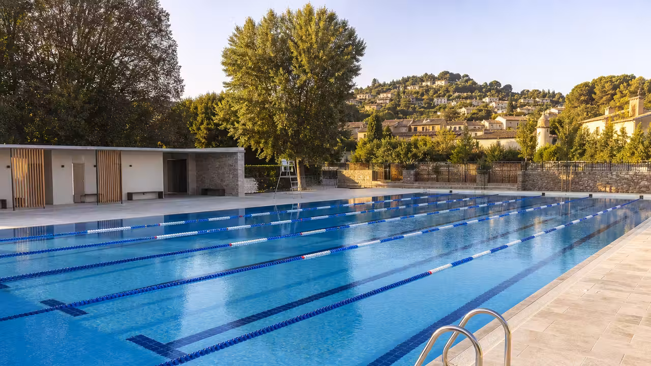 Bassin extérieur d’une piscine municipale préparé pour l’ouverture estivale, avec lignes d’eau et plages vides
