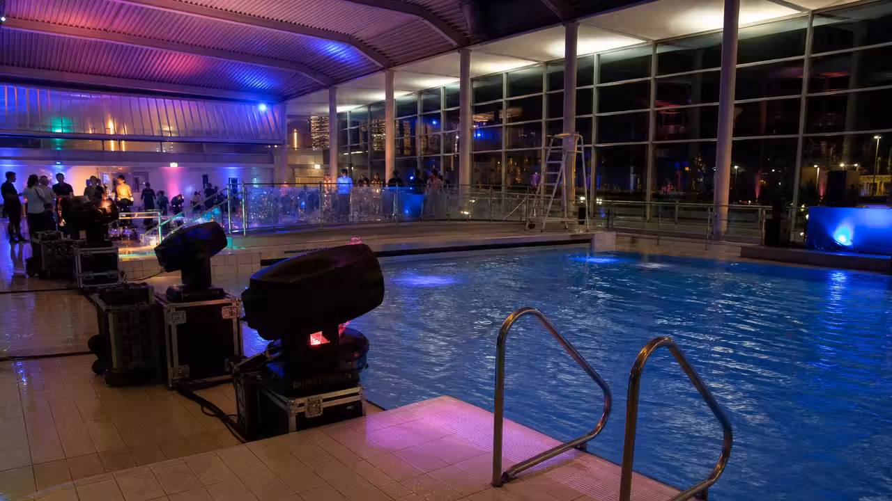 Bassin intérieur d’un centre aquatique éclairé en soirée, prêt pour une animation festive encadrée