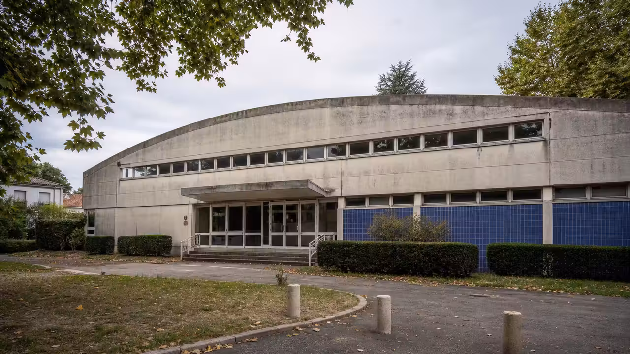 Ancien bâtiment de piscine municipale en cours d’évaluation dans un quartier urbain arboré