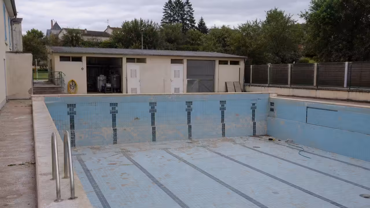 Bassin municipal vide en rénovation, avec plages carrelées et équipements techniques visibles à Barbezieux