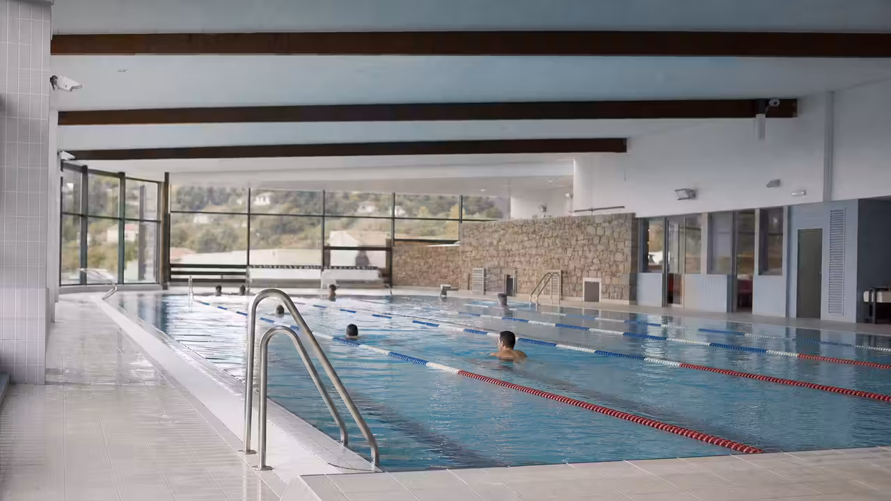 Intérieur lumineux d’une piscine publique rénovée avec lignes d’eau, plages claires et baies vitrées