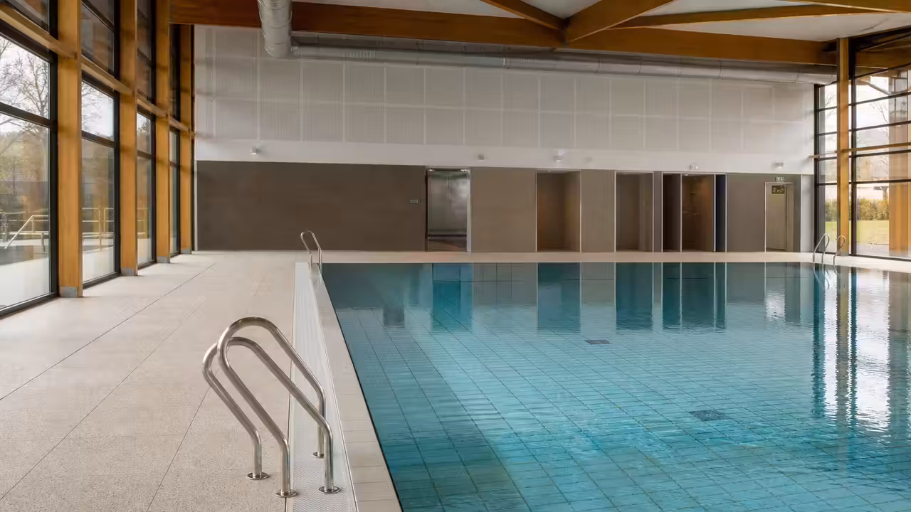 Bassin d’une piscine municipale rénovée rempli d’eau claire, avec plages et équipements techniques neufs