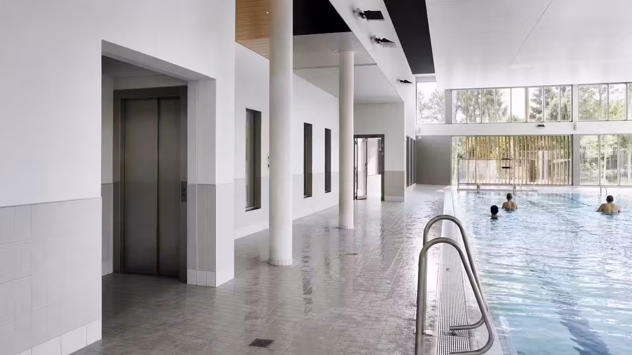 Intérieur rénové d’une piscine publique avec sols antidérapants, douches modernes et accès accessible