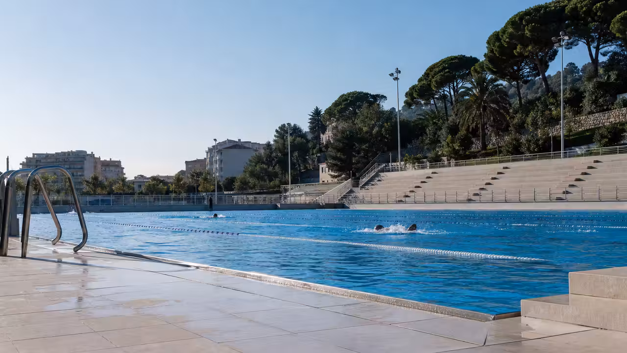 Bassins extérieurs rénovés d'une piscine municipale avec plages carrelées et éclairage moderne à Nice