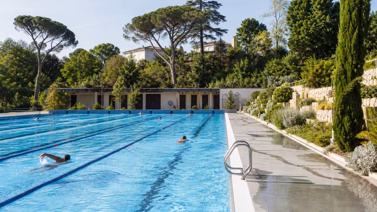 Nageurs dans un bassin municipal rénové, avec lignes d’eau et végétation sur les hauteurs de Toulouse