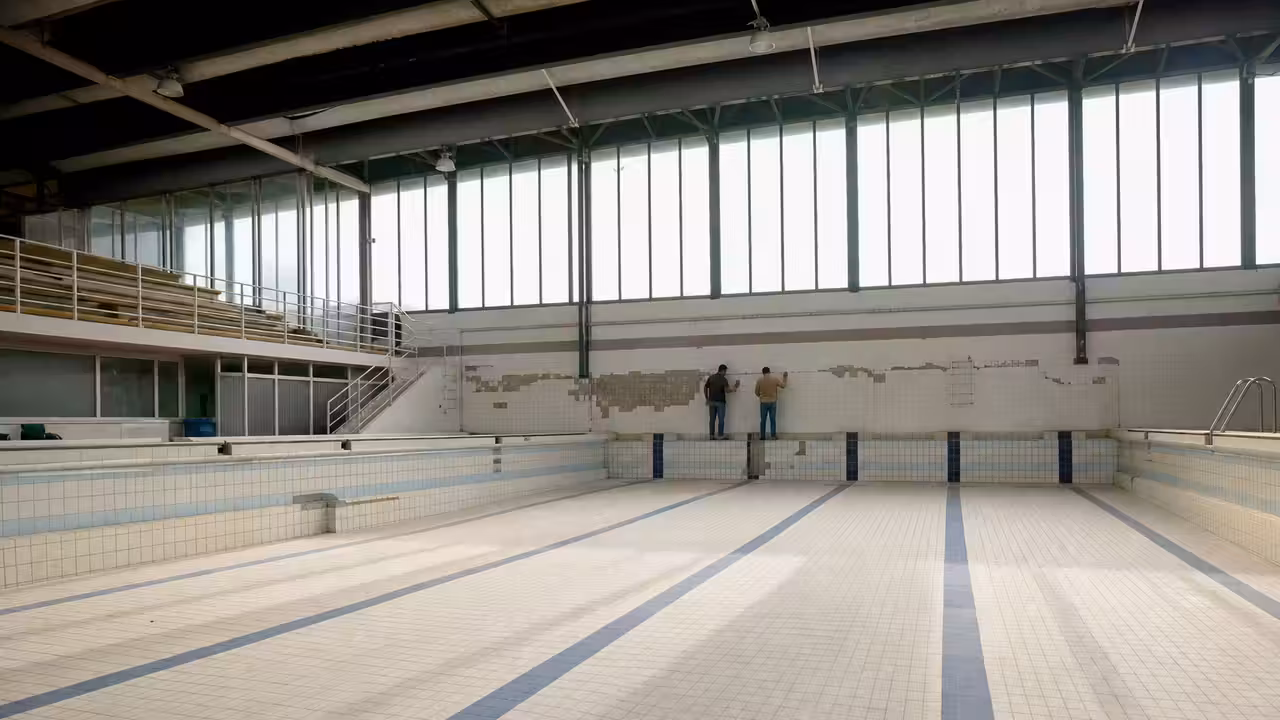 Bassin municipal vide lors d’une inspection technique, avec carrelage ancien et fissure visible au sol