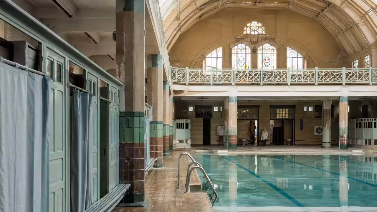 Bassin intérieur historique avec voûte lumineuse, carrelage ancien et vitraux décoratifs à Paris