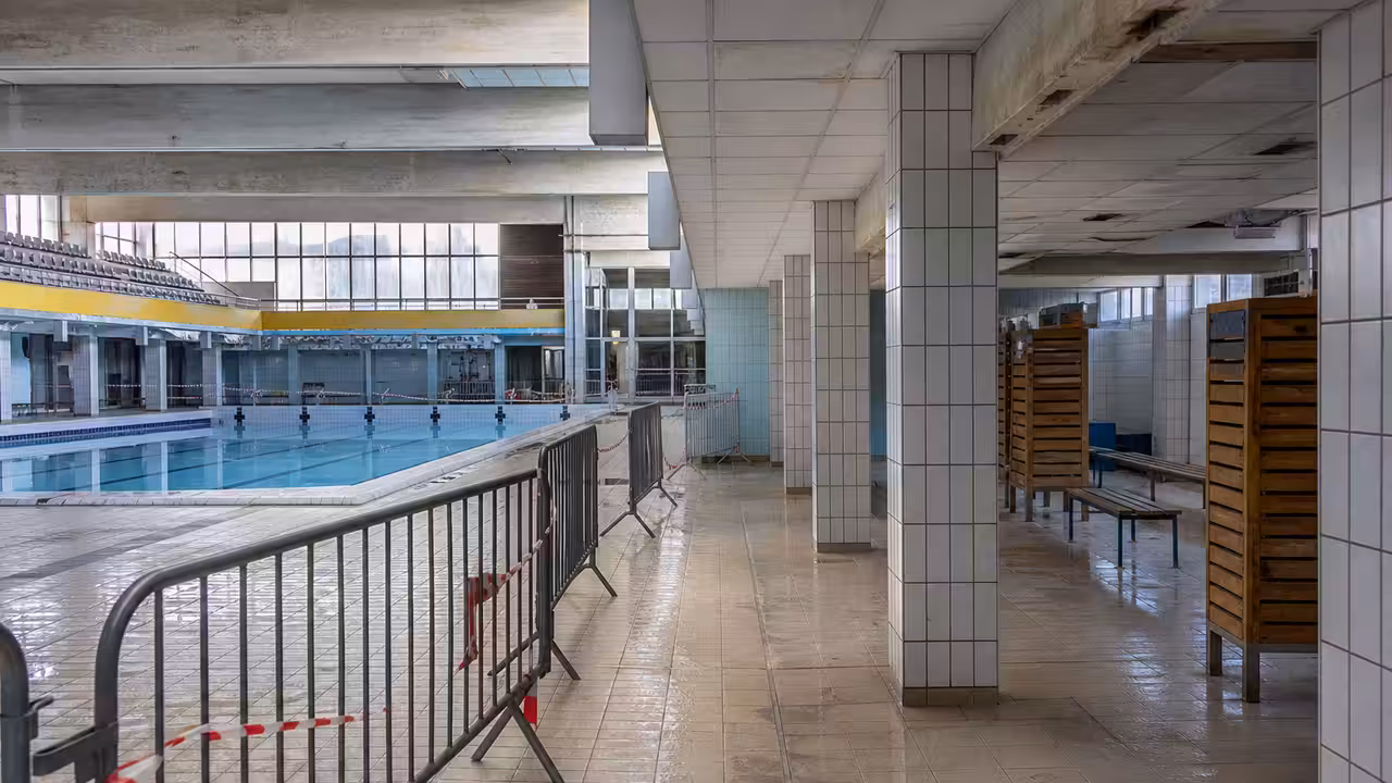 Hall d’une piscine municipale fermé avec sol humide et zone de plafond mise en sécurité
