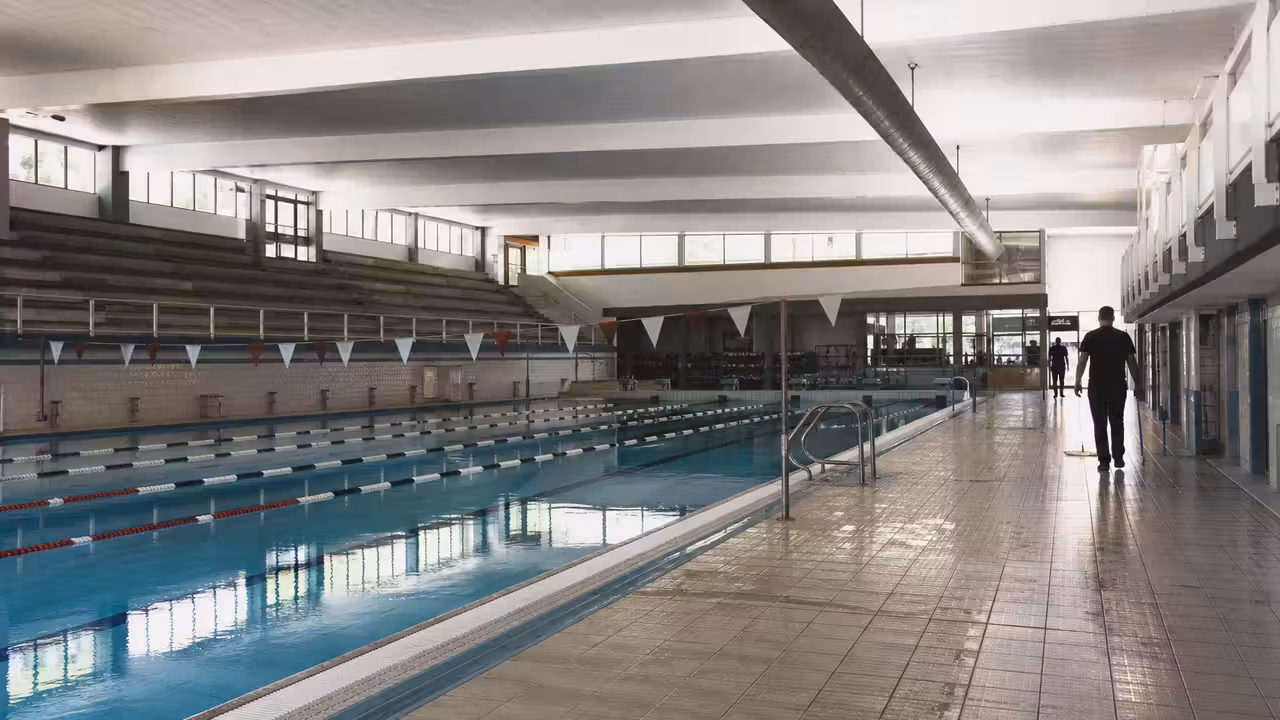 Bassin couvert d’une piscine publique, lignes d’eau et gradins vides avant l’ouverture au public