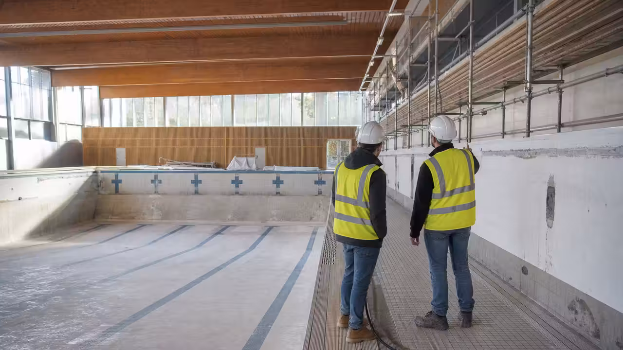 Bassin d’une piscine municipale en rénovation, avec échafaudages et équipes techniques au travail