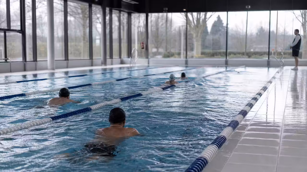 Nageurs dans les lignes d’eau d’une piscine couverte lumineuse lors d’une reprise d’activité