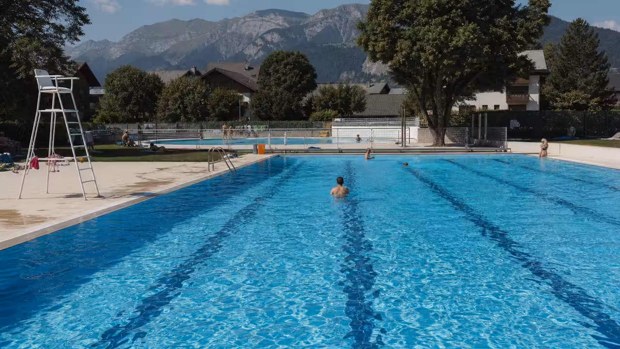 Bassin extérieur de 25 mètres entouré d’arbres et de plages de repos dans une piscine municipale estivale
