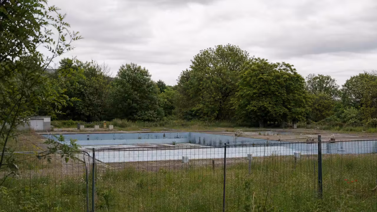 Ancien site de piscine urbaine bordé d’arbres, illustrant le choix entre parc public et construction