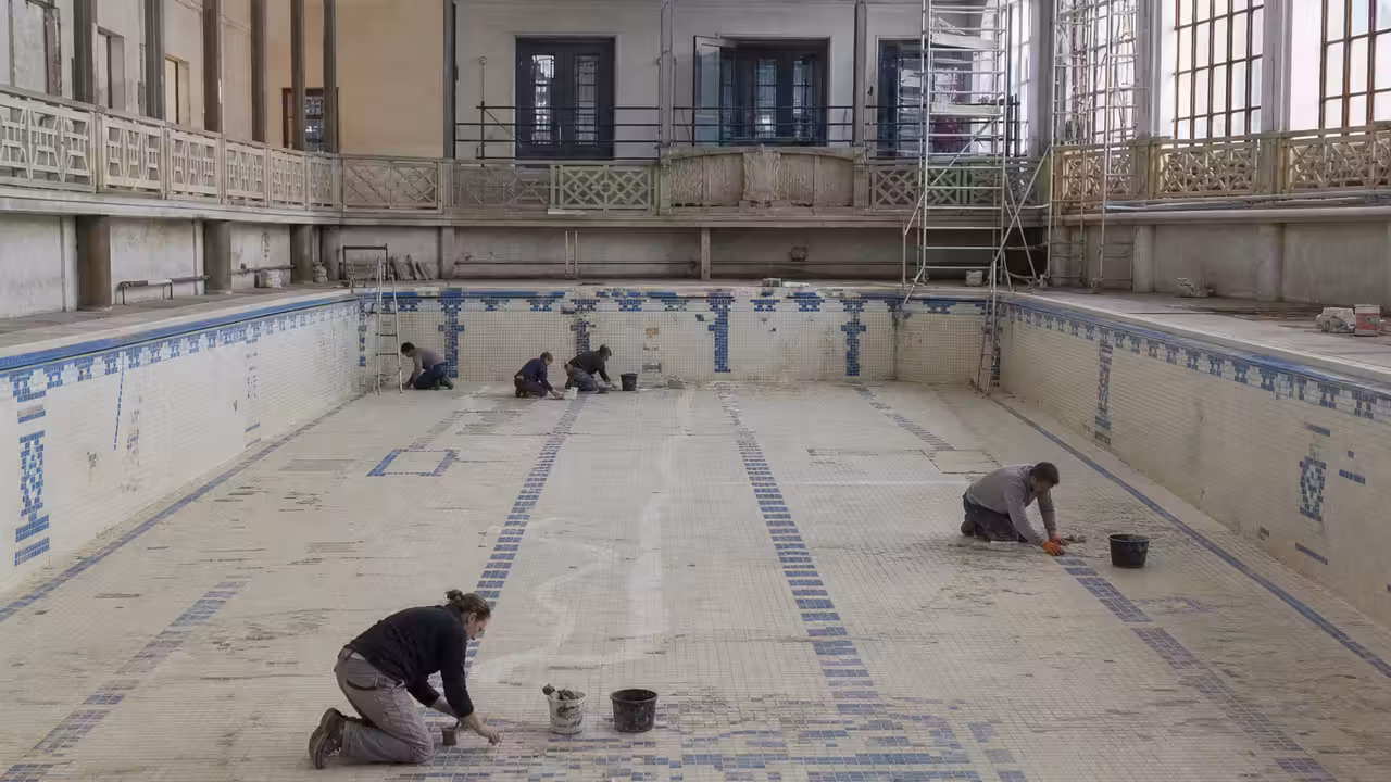 Bassin Art déco ancien en rénovation, avec mosaïques préservées et échafaudages sous une verrière