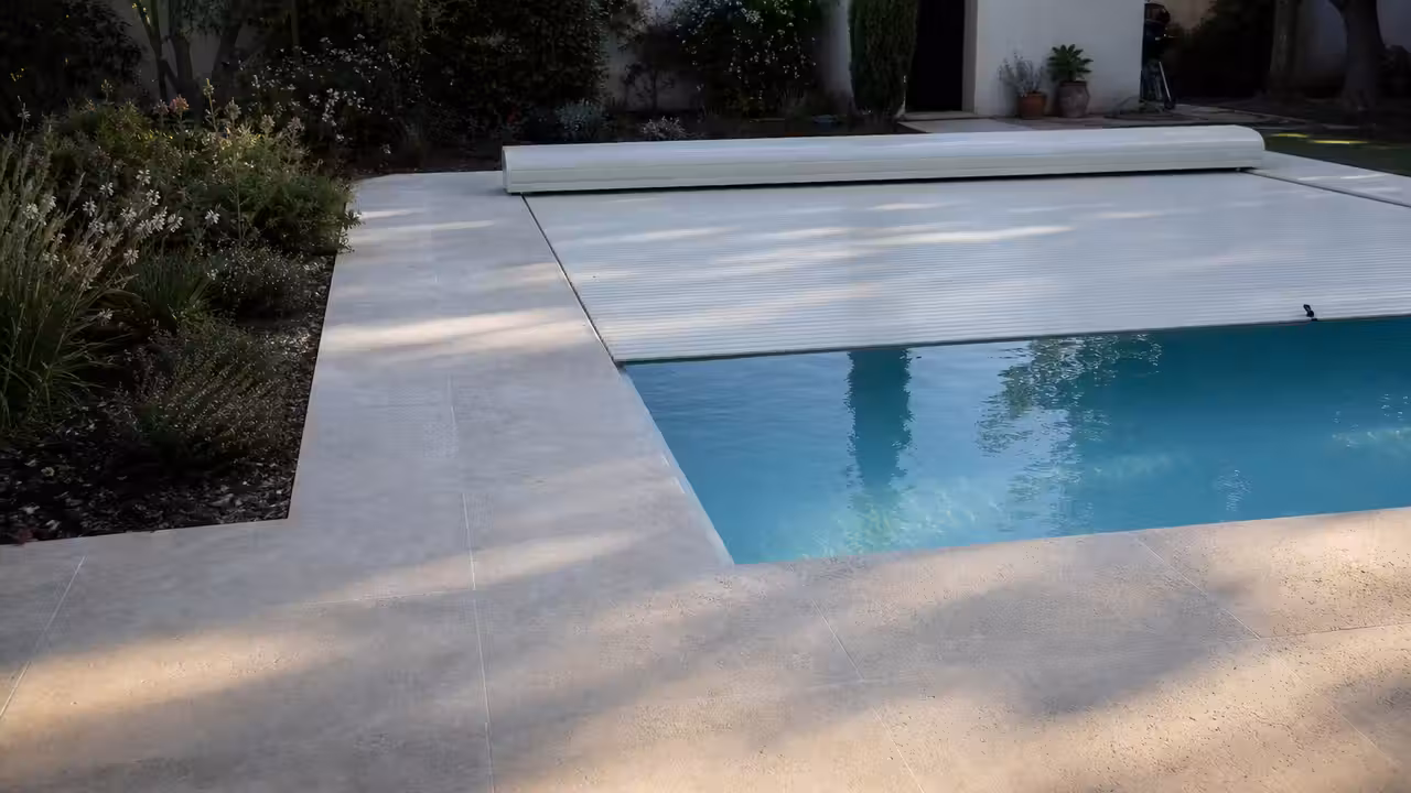 Piscine familiale contemporaine couverte dans un jardin, avec local technique discret et terrasse minérale