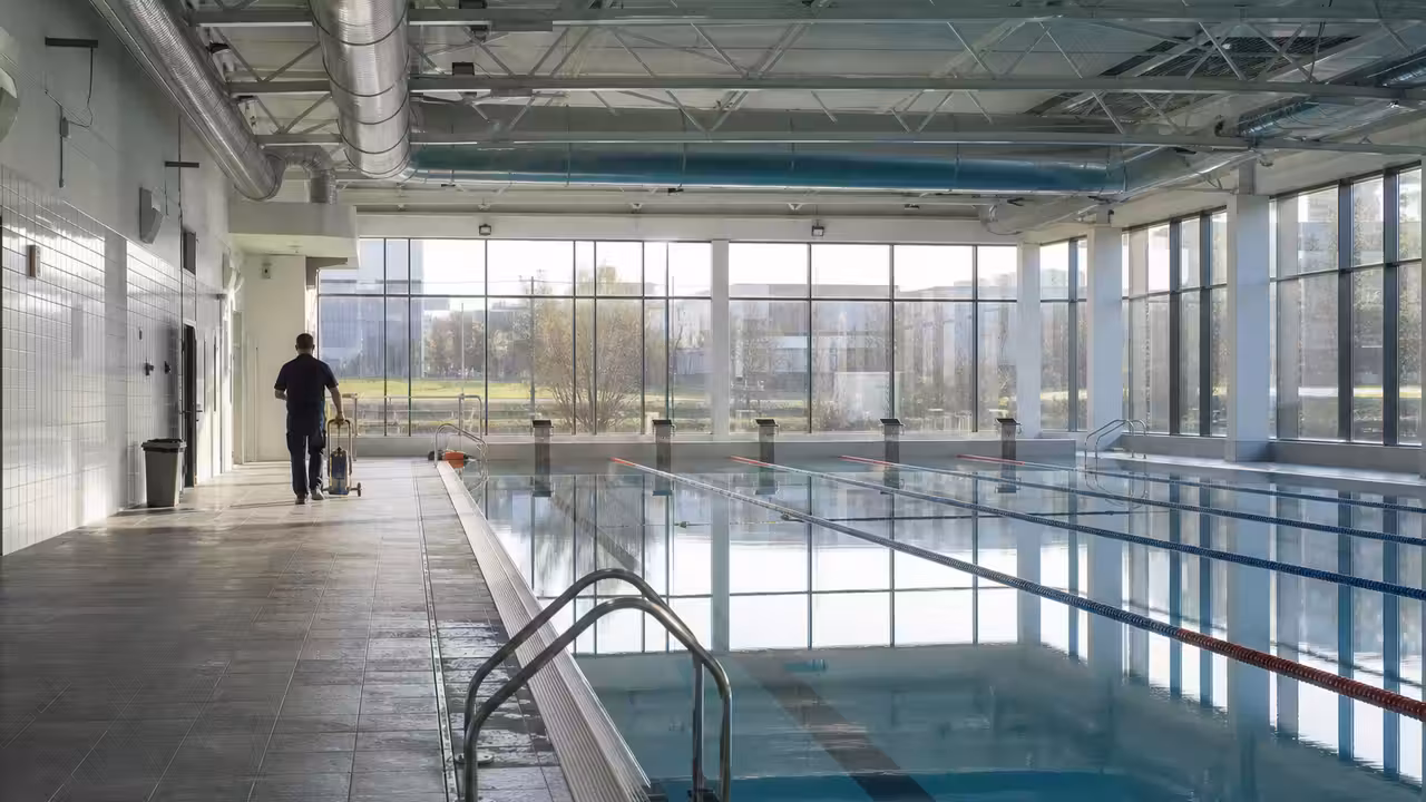 Bassin intérieur d’une piscine publique avec lignes d’eau, baies vitrées et équipements techniques discrets