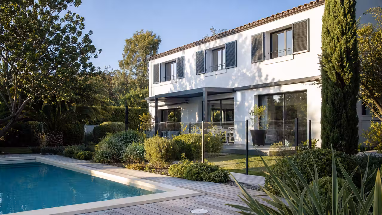 Maison contemporaine avec piscine enterrée, terrasse aménagée et jardin entretenu vus en lumière de fin d'après-midi