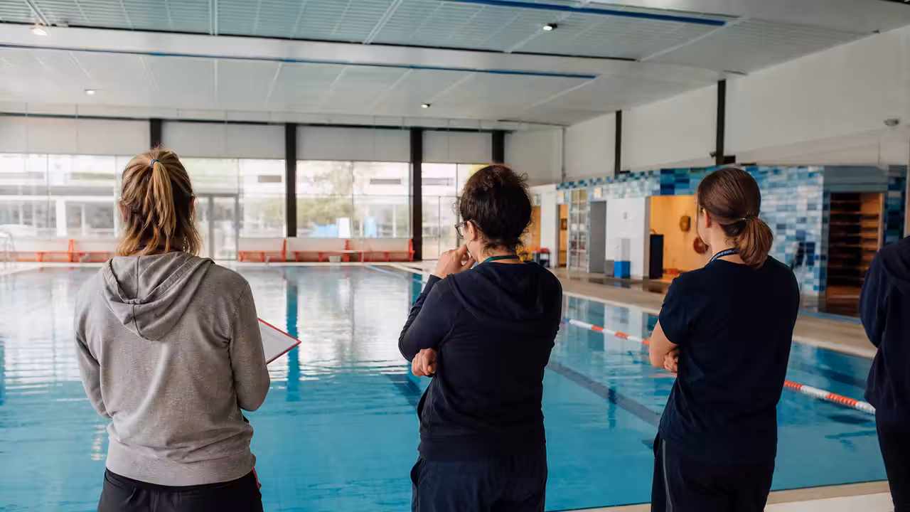 Enseignants préparant une séance de natation sur le bord d’un bassin municipal couvert et lumineux