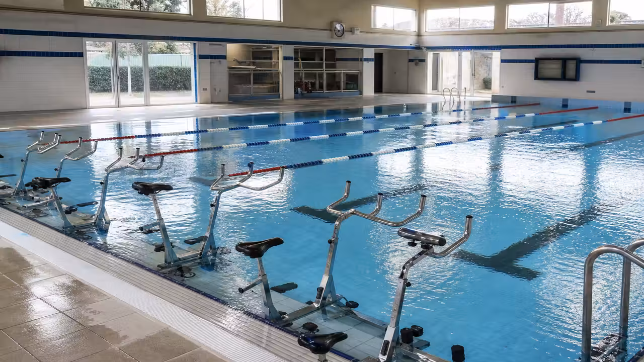 Bassin intérieur de piscine publique avec lignes d’eau et vélos d’aquabike rangés sur le bord