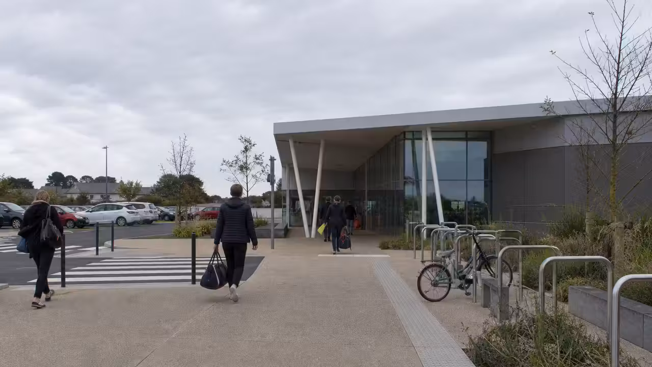Accès piéton et piste cyclable devant un centre aquatique public contemporain en milieu urbain