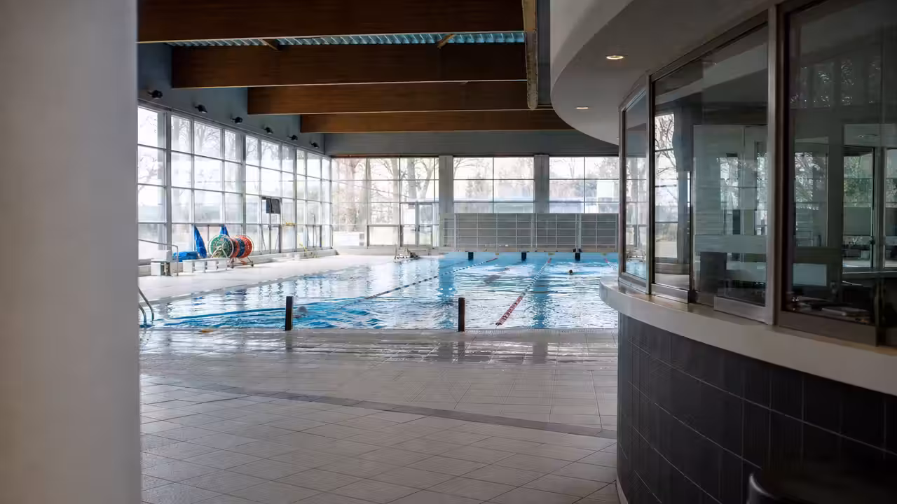 Bassin couvert d’une piscine municipale avec lignes d’eau, gradins et guichet d’accueil en arrière-plan
