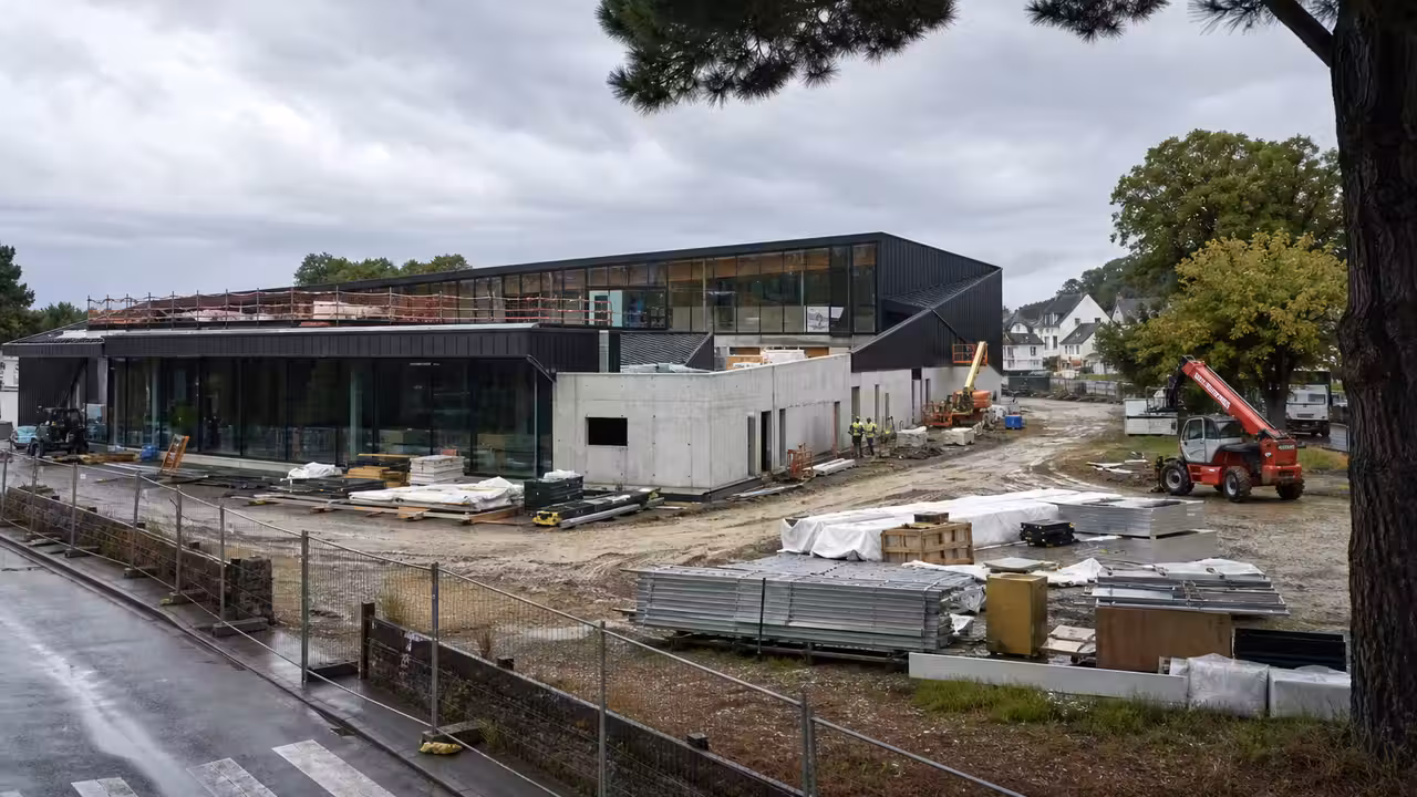 Vue d’ensemble d’un chantier de centre aquatique urbain près d’une zone d’activités et d’arbres