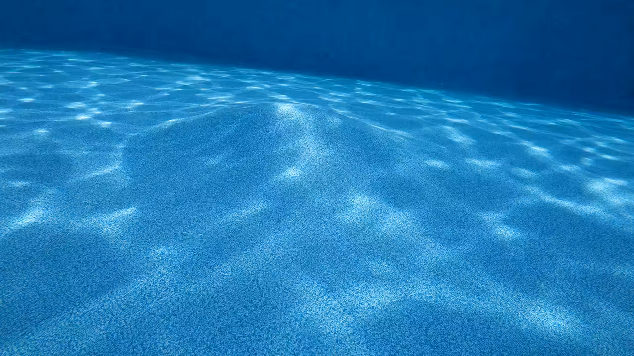 Fond de piscine avec un liner bleu présentant une légère déformation en forme de bosse près du centre