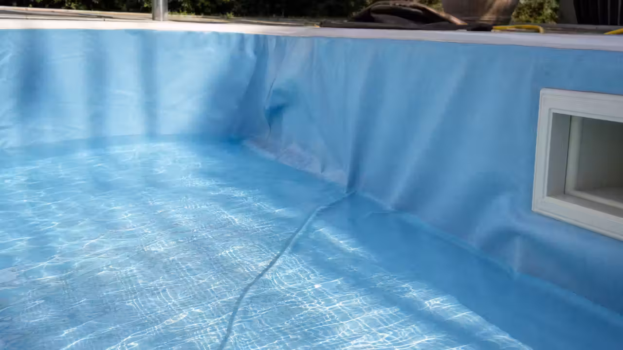 Gros plan sur un pli du revêtement PVC au fond d'une piscine en cours de remplissage, eau translucide