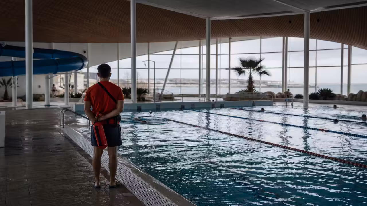 Bassin intérieur lumineux d’un centre aquatique avec couloirs de nage et espace ludique en arrière-plan