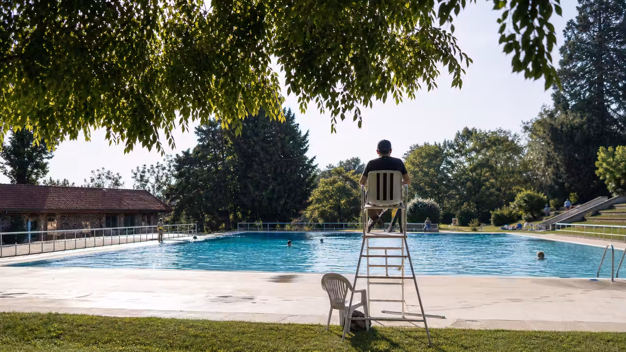 Bassin extérieur d’une piscine publique entouré de pelouses, prêt à accueillir les baigneurs en été