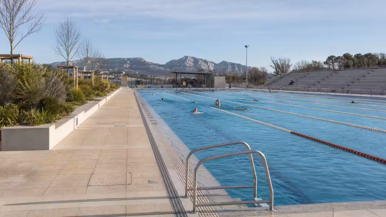 Bassin extérieur de 50 mètres d’un centre aquatique moderne, bordé de plages minérales et végétalisées