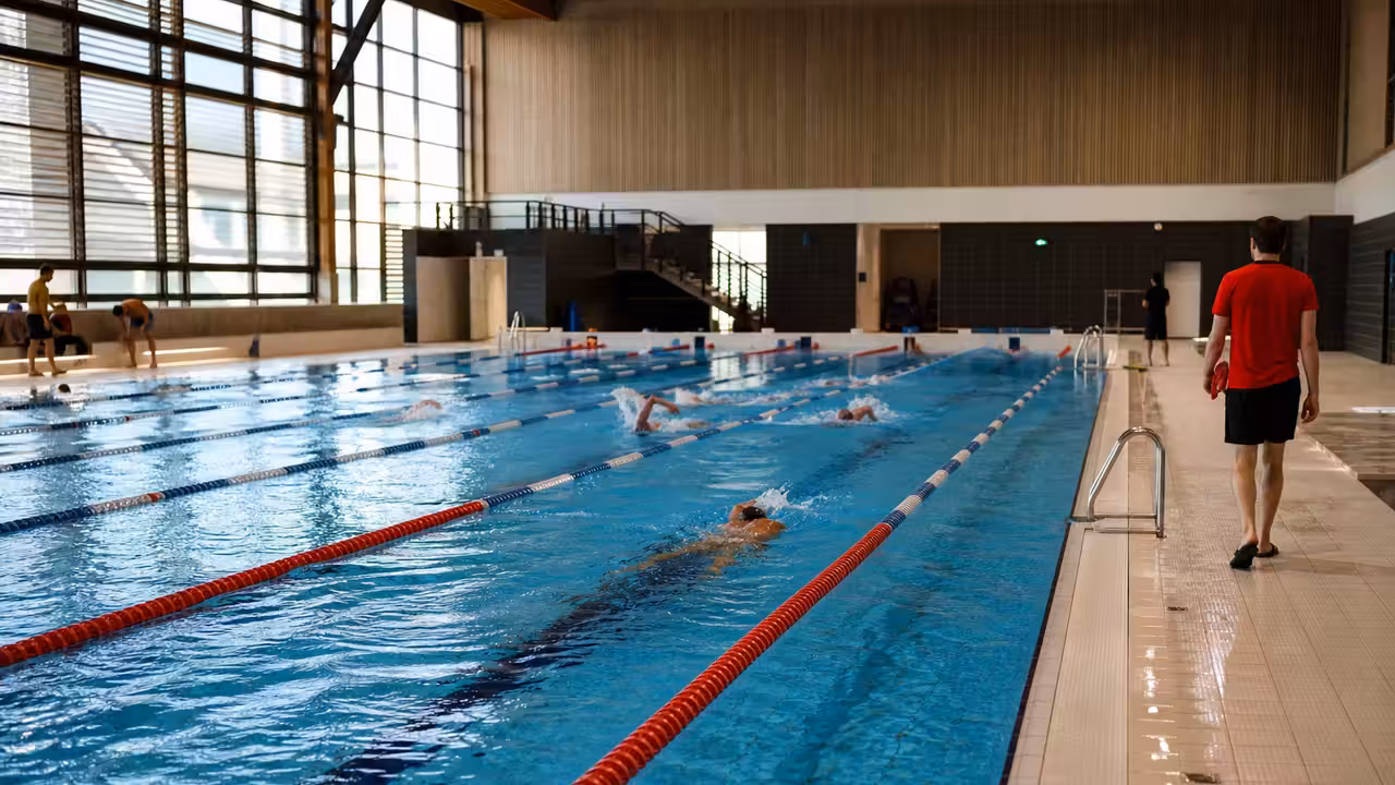 Lignes d’eau d’un bassin intérieur avec nageurs adultes dans un centre aquatique lumineux