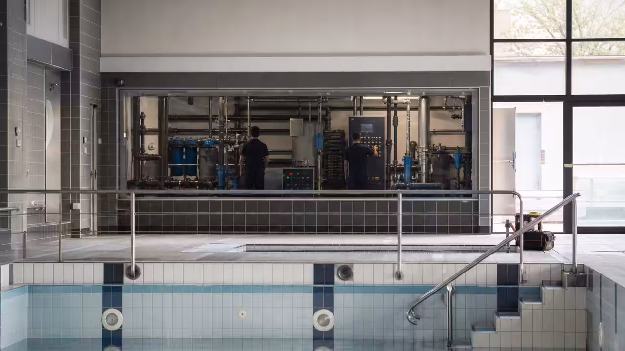 Grand bassin couvert vide dans un centre aquatique moderne, avec lignes d’eau et équipement de filtration