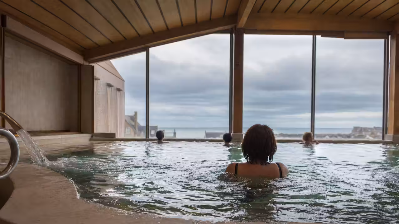 Bassin intérieur chauffé avec jets de massage, éclairé par une douce lumière naturelle latérale