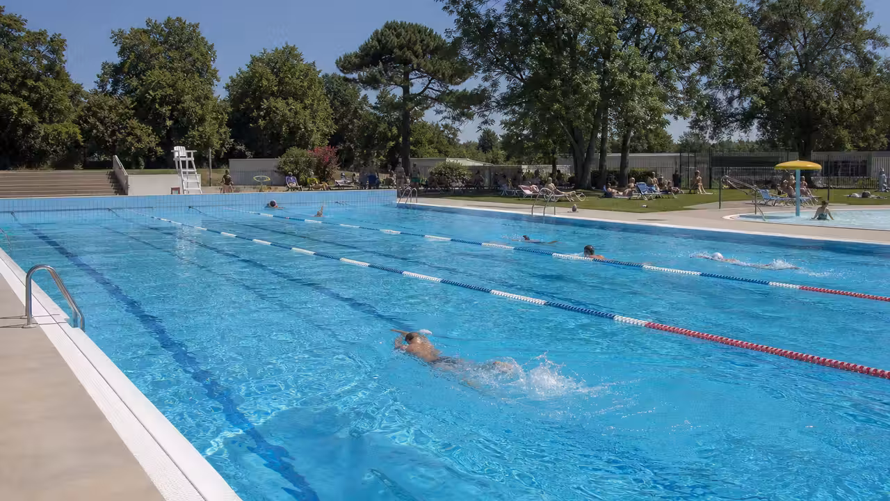 Bassin extérieur de 25 mètres d’une piscine municipale animé par des nageurs durant une journée d’été