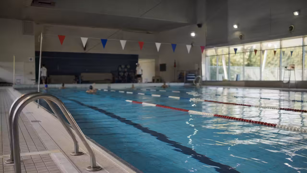 Couloirs d’un bassin municipal intérieur réservés en journée, sans nageur au premier plan
