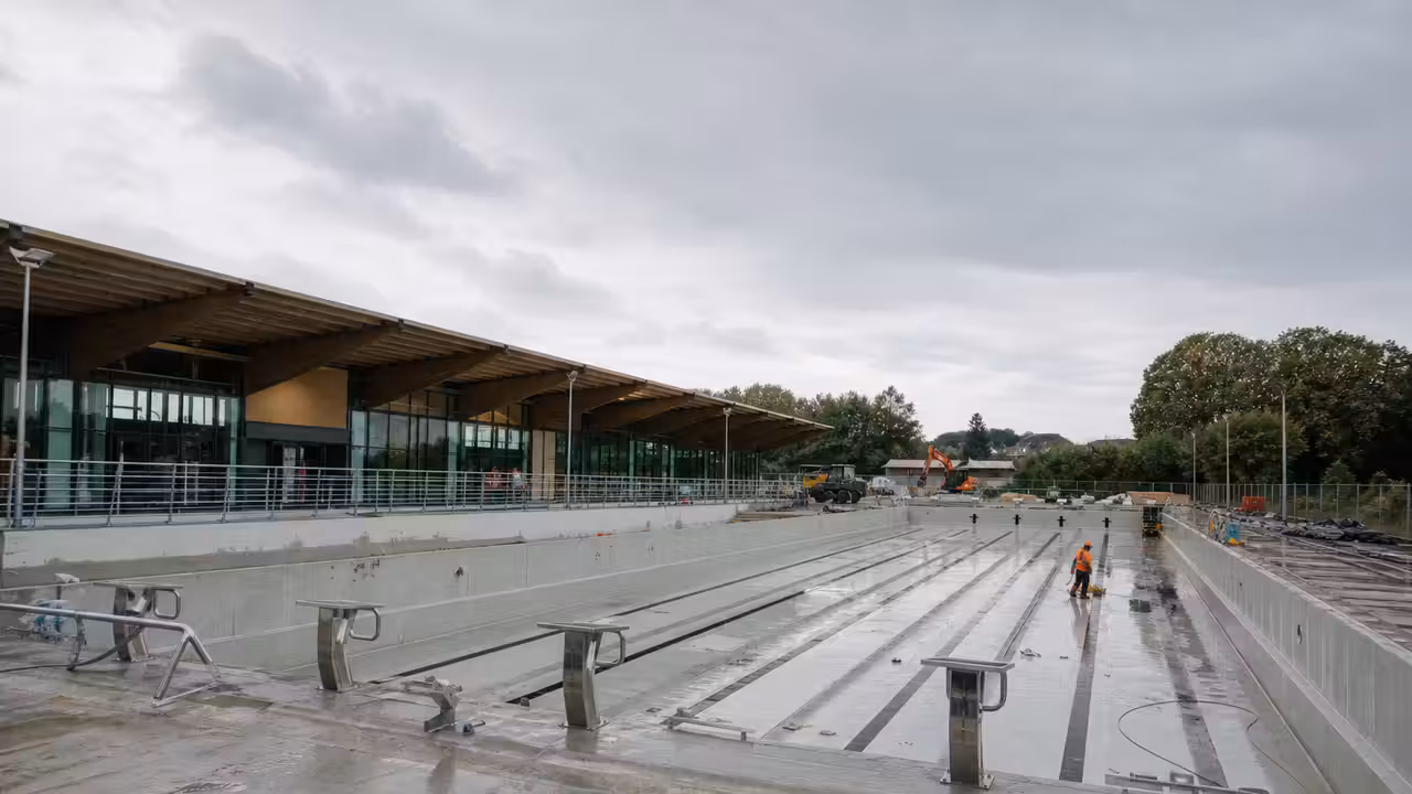 Chantier d’un centre aquatique moderne avec bassin extérieur de 50 mètres et structure intérieure en arrière-plan