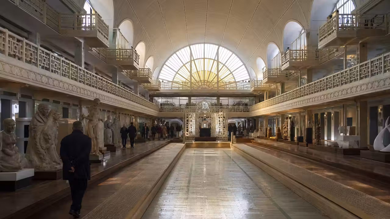 Vue intérieure d’un ancien bassin Art déco reconverti en espace muséal, éclairé par une grande verrière