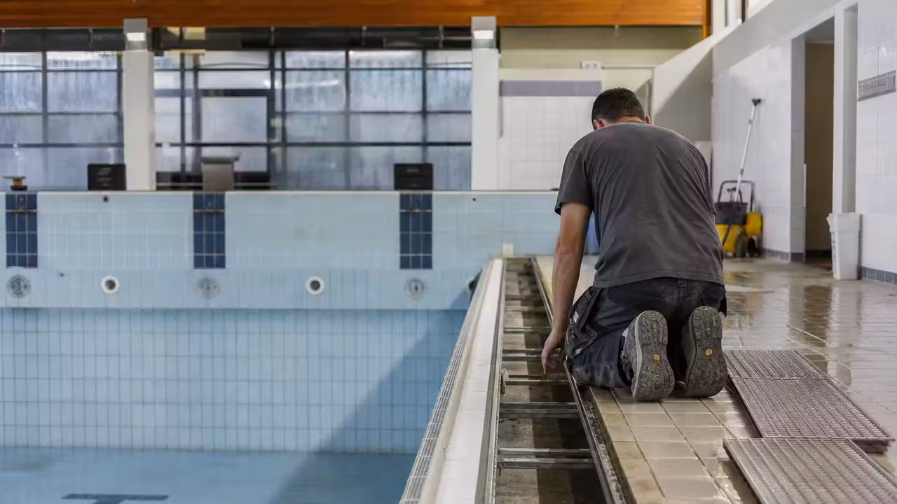 Caniveau de débordement vide au bord d’un bassin public pendant une intervention de maintenance technique