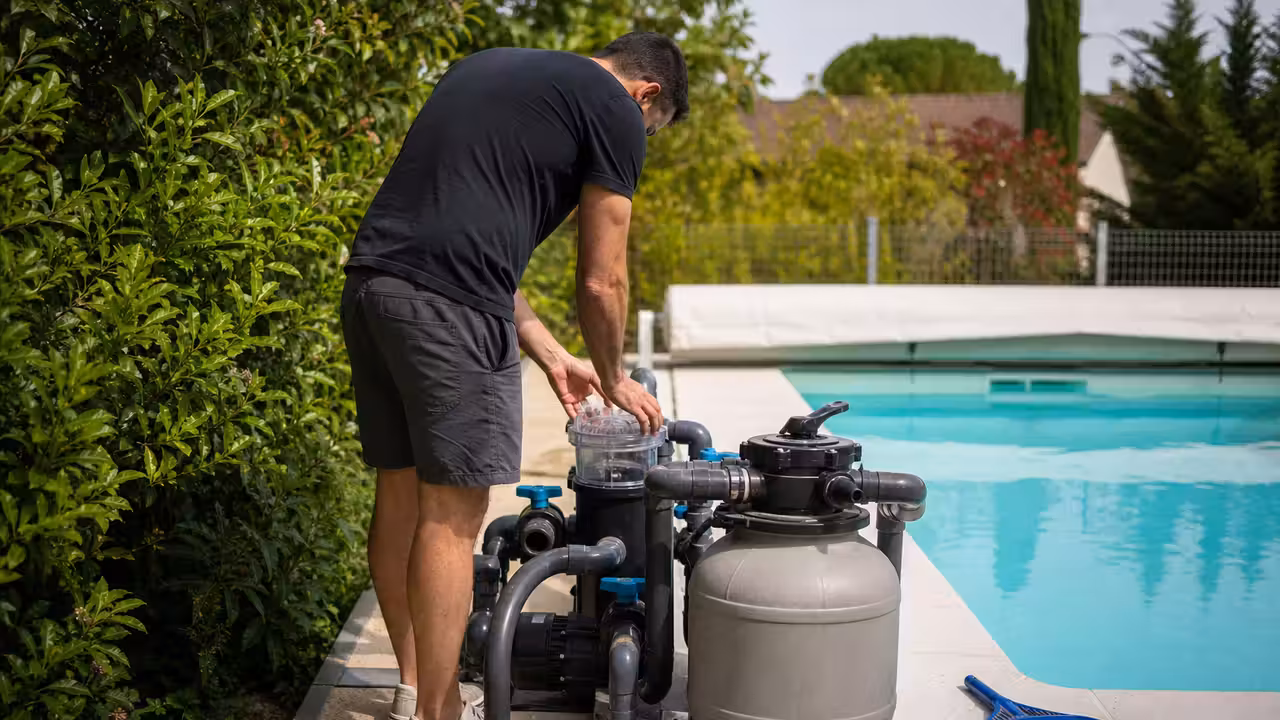 Propriétaire contrôlant la pompe et le filtre d’une piscine lors de sa remise en service au printemps