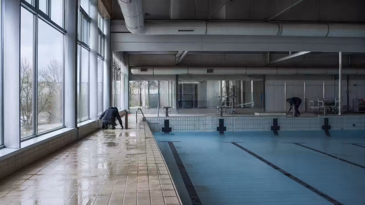 Bassin couvert de piscine municipale avec lignes d’eau, baies vitrées et équipements techniques en arrière-plan
