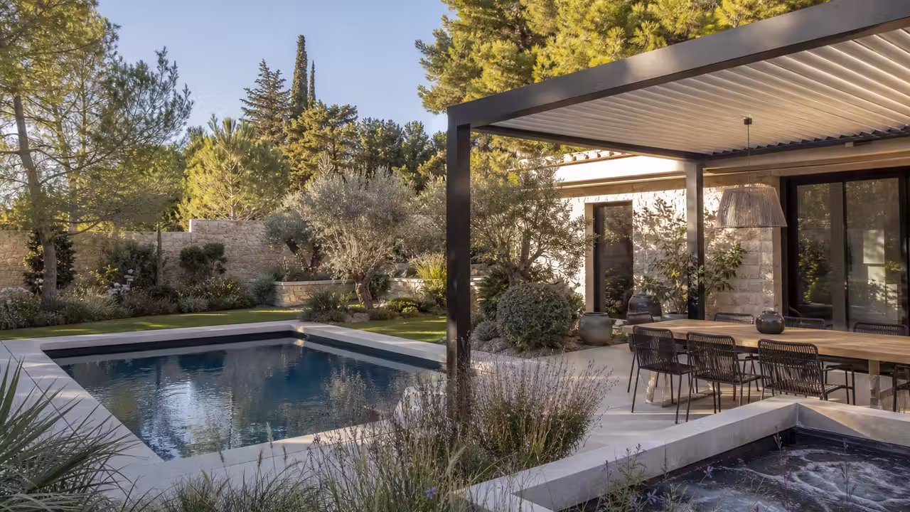 Piscine rectangulaire bordée de pierre claire, pergola à lames et spa intégré dans un jardin planté.