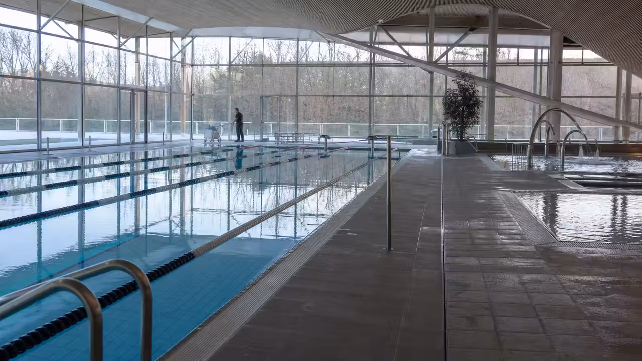 Grand bassin couvert d’un centre aquatique baigné de lumière avant l’ouverture au public