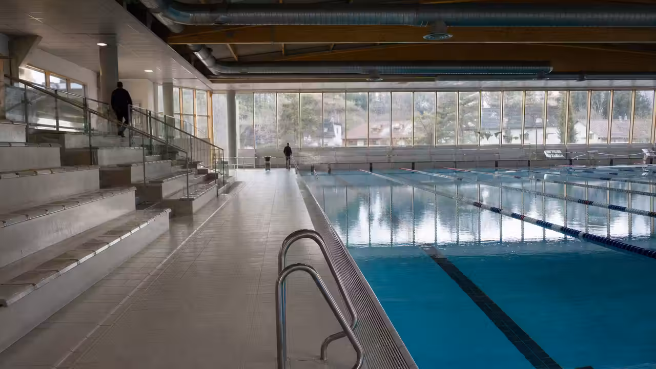 Bassin couvert d’une piscine publique avec lignes d’eau, gradins discrets et grandes baies vitrées