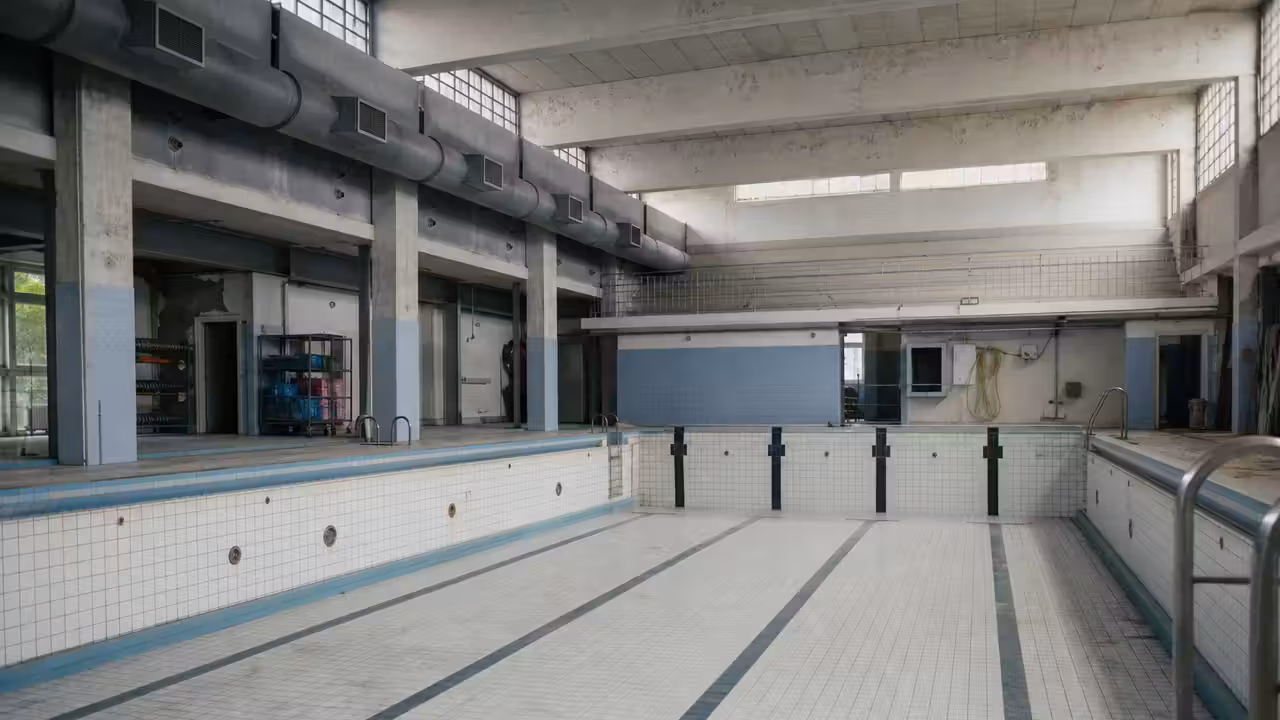 Bassin de piscine publique avec rampe d’accès, couloir de nage et vestiaires accessibles en arrière-plan