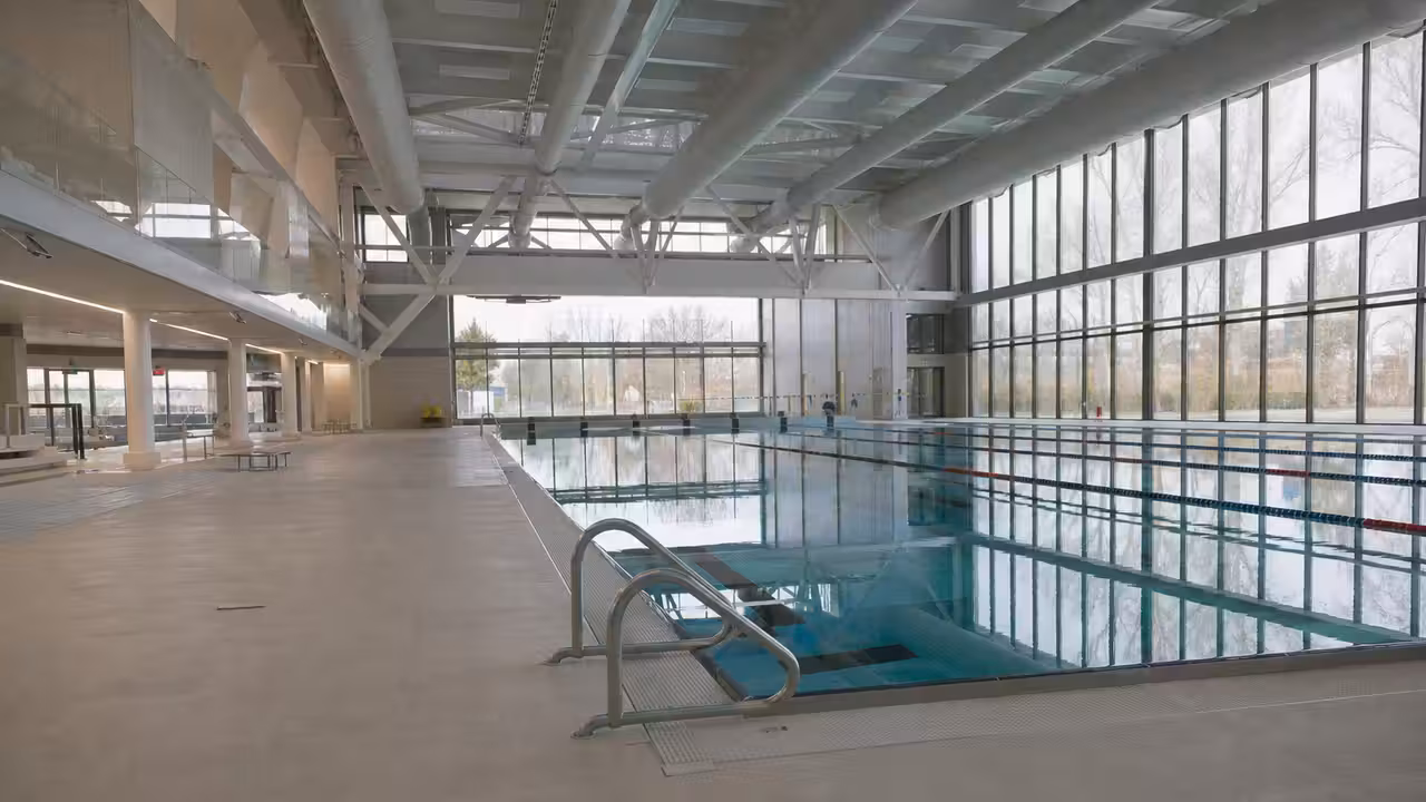 Bassin couvert de 50 mètres avec lignes d’eau et grandes baies vitrées dans un centre aquatique municipal
