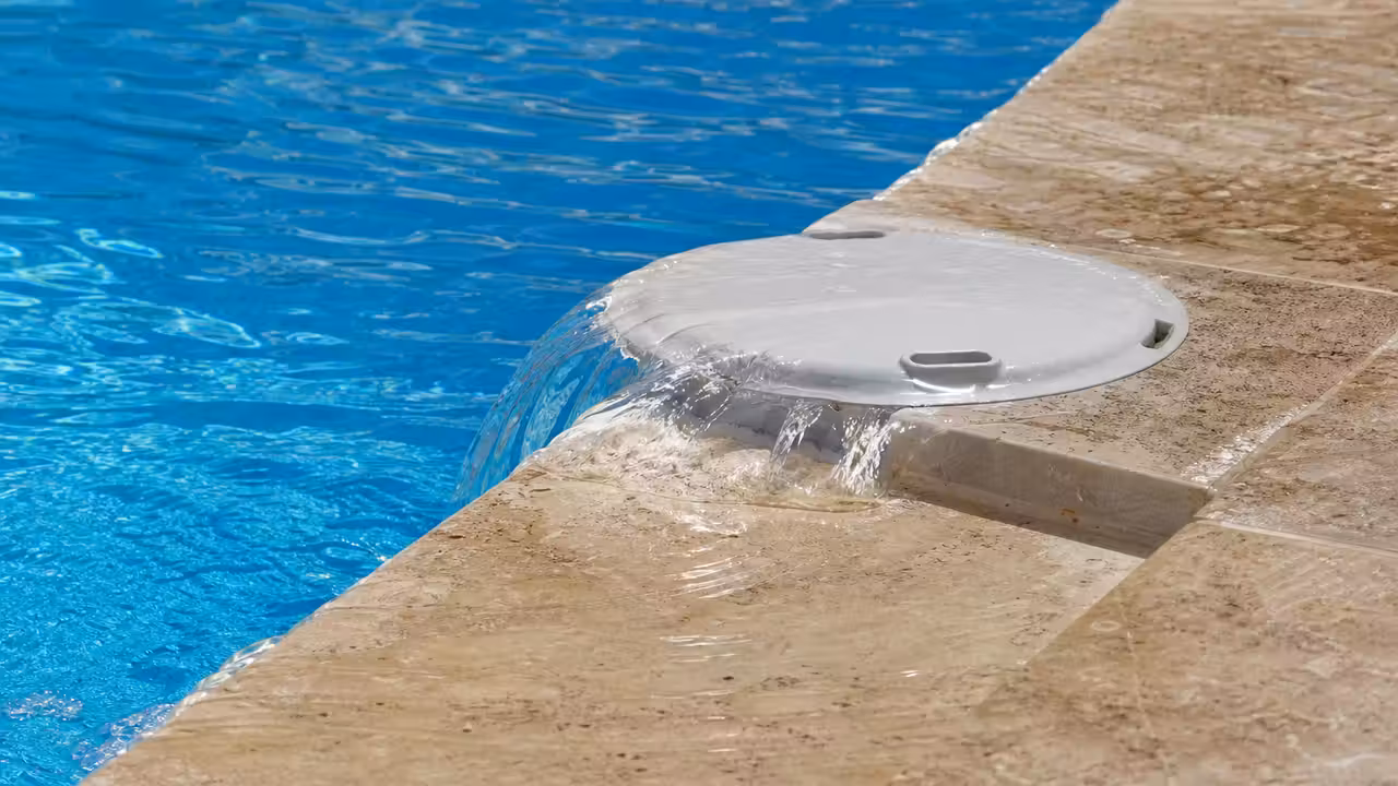 Eau qui déborde de la bouche d'un skimmer de piscine sur la margelle, niveau d'eau visiblement trop haut
