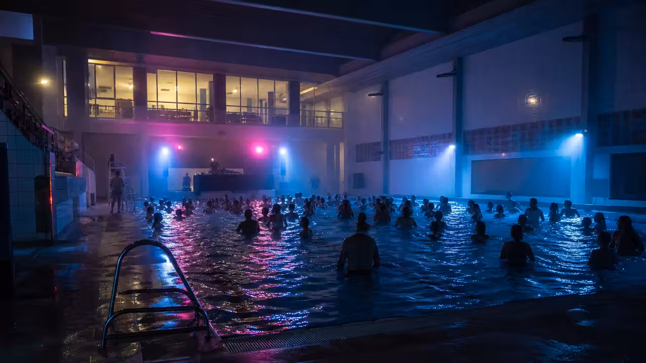 Bassin municipal éclairé de néons lors d’une animation aquatique nocturne avec participants adultes