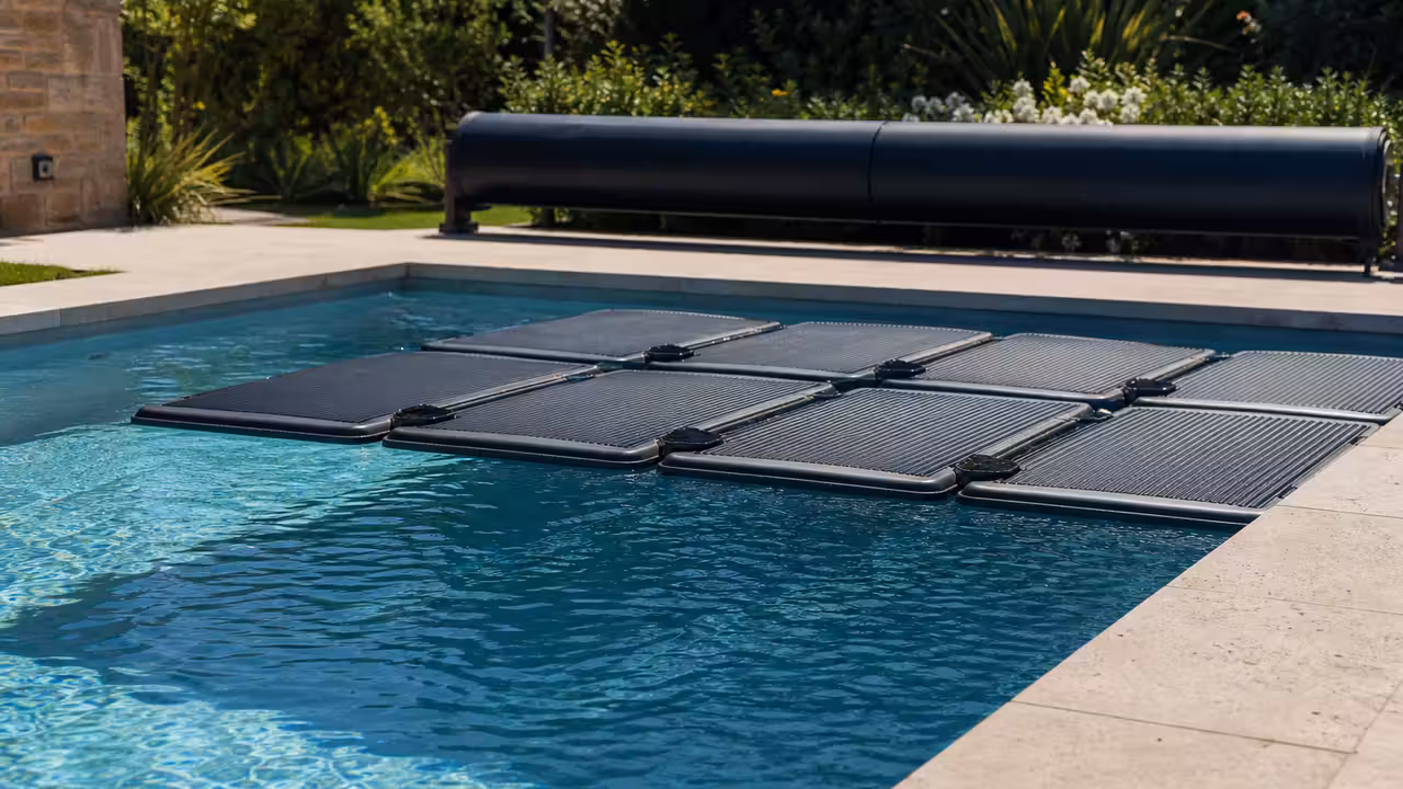 Dispositif solaire flottant sur une piscine familiale, sous un soleil d’été avec couverture enroulée au bord
