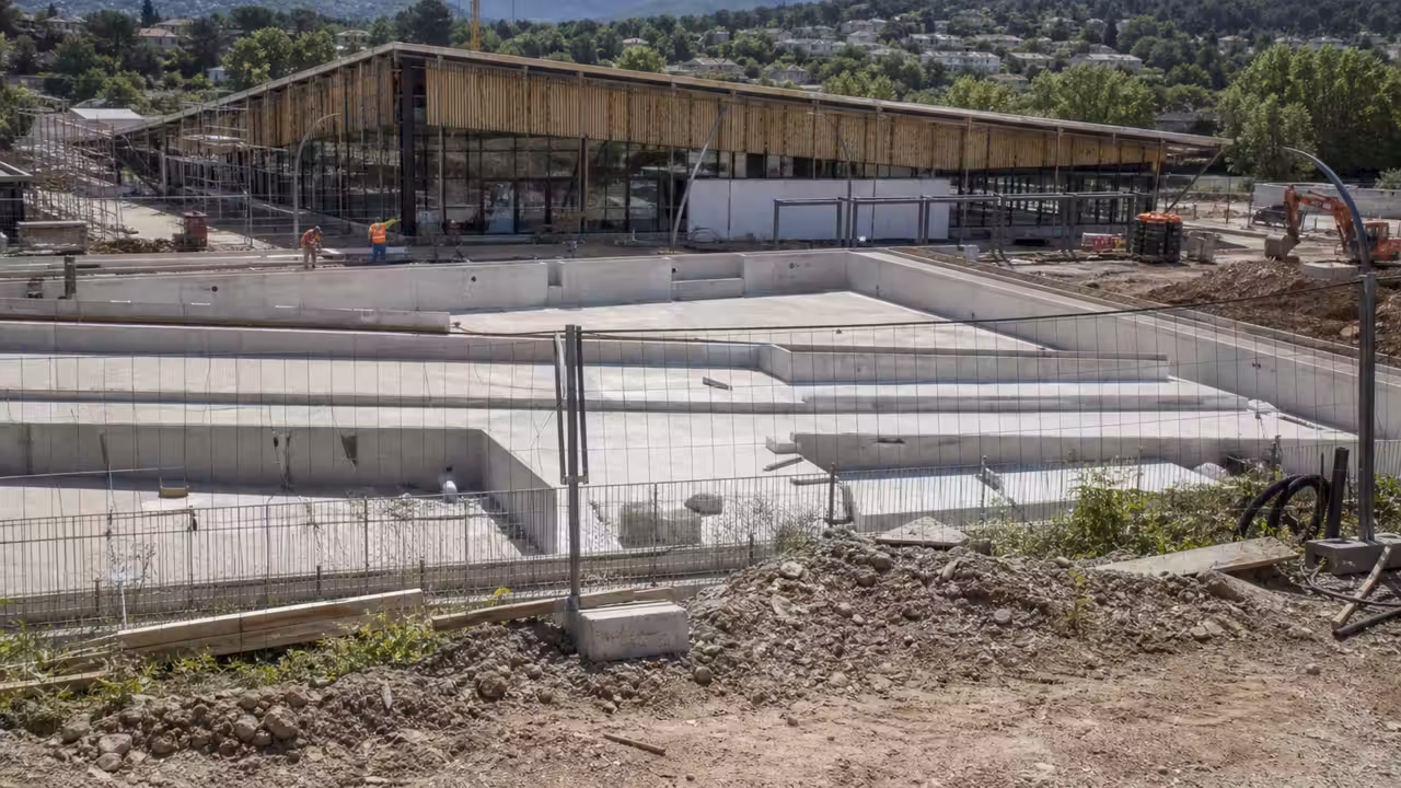 Chantier d’un futur centre aquatique public avec structure métallique et bassins en cours de réalisation